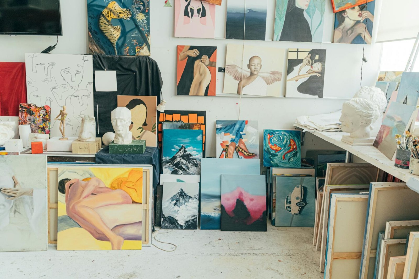 A vibrant art studio featuring diverse paintings, sculptures, and artistic materials in an indoor setting.