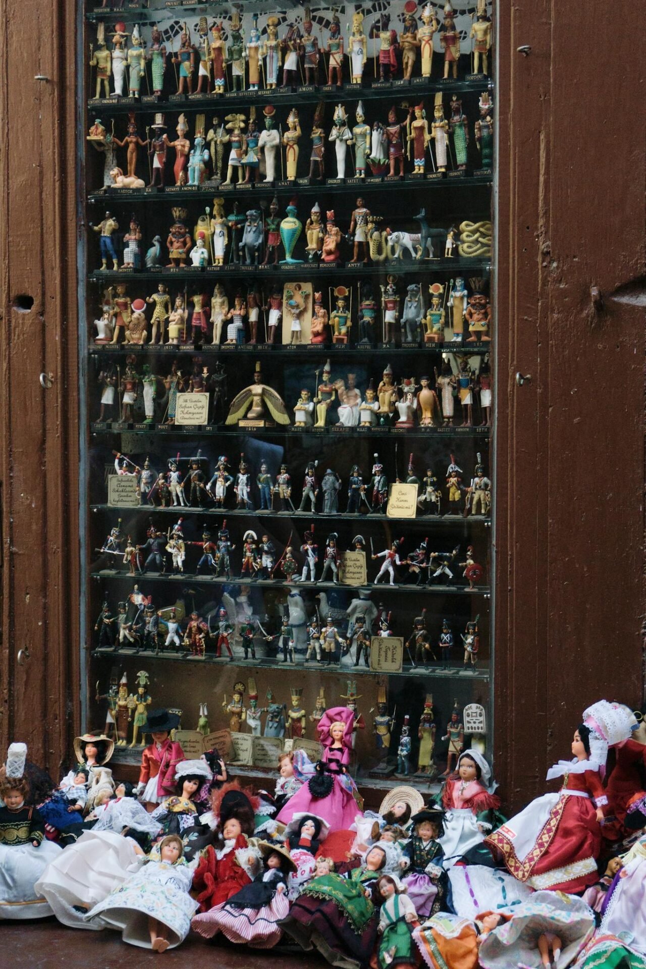 Vibrant display of various cultural miniature dolls and figurines in a shop window, showcasing diverse traditions.